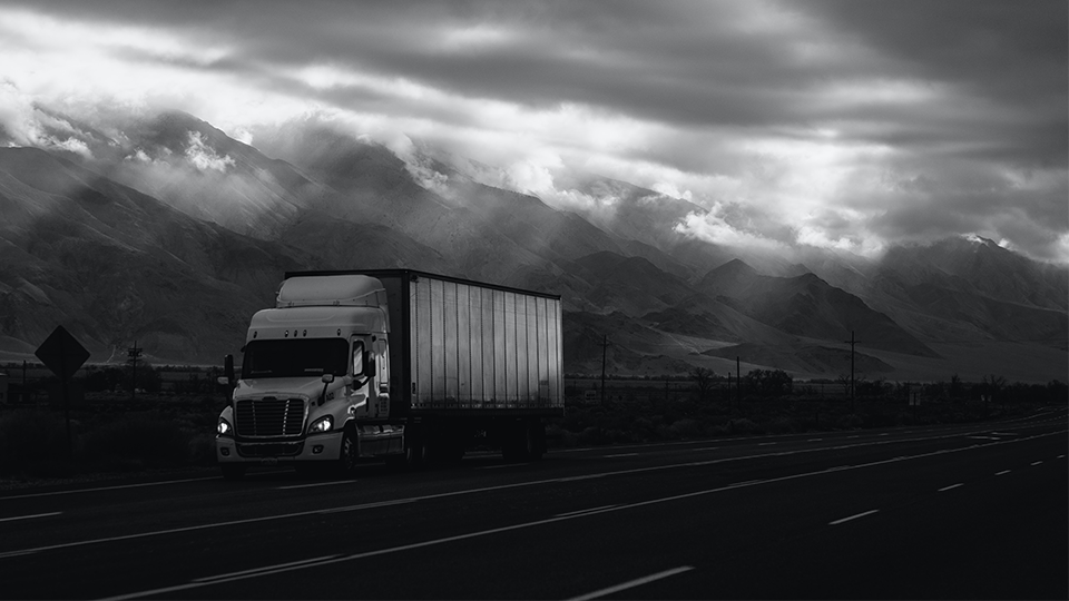 Semi truck on the highway at night light through clouds