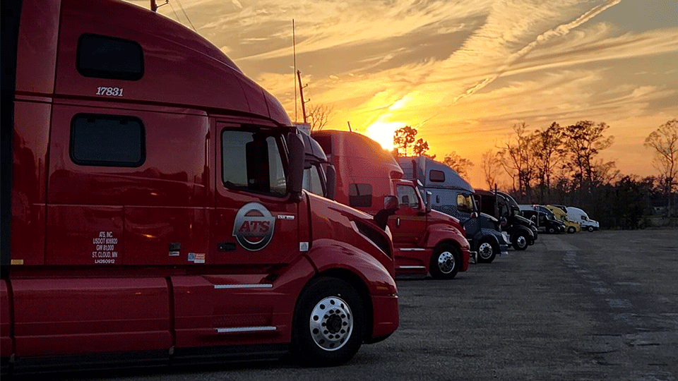 ten-semi-trucks-parked-in-row-at-sunset